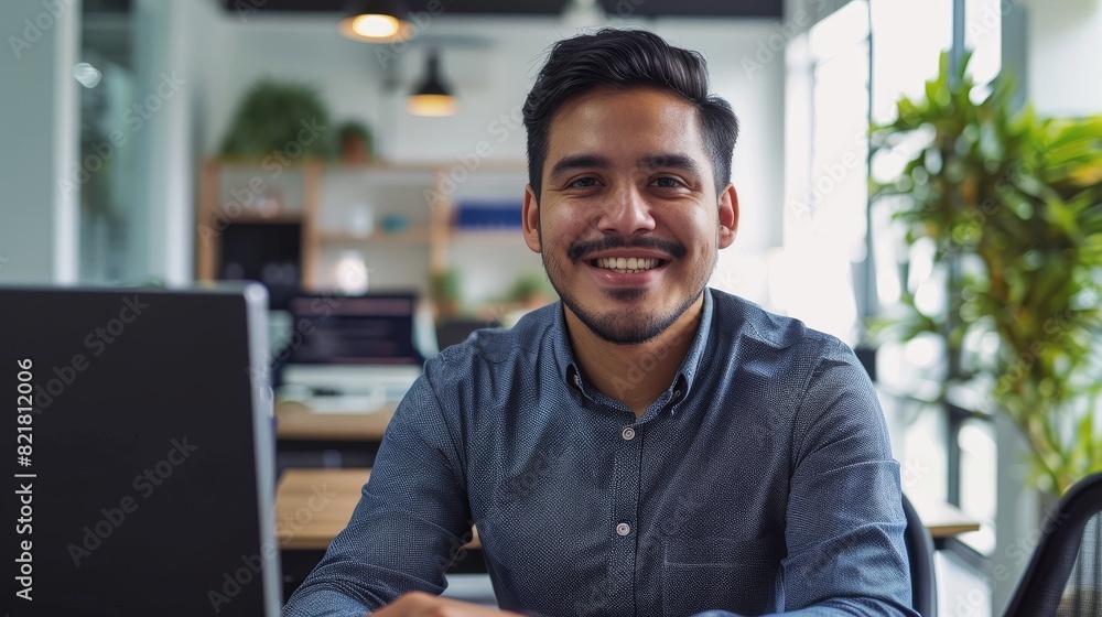 Poster angry office businessman smiling at camera. latin it software engineer working at his desk on a lapt