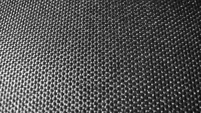 A mesmerizing macro capture of black polyester fabric reveals a dense and meticulous weave. Its smooth surface gleams subtly, showcasing resilience for diverse uses.
