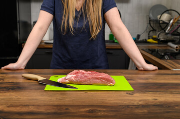 Łopatka wieprzowa surowa na gulasz, kobieta stoi w kuchni i przygotowuje obiad z mięsa
