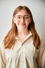 Portrait of beautiful girl smiling to camera. Cute girl in cream shirt and square glasses posing on white background.