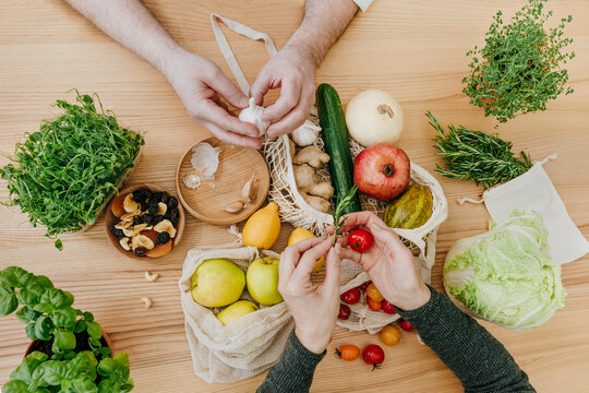 Hands of couple with fruits and vegetables on table at home - Powered by Adobe