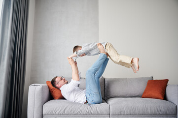Joyful father lifting happy little son at home. Carefree father and son weekend. Happy young father...