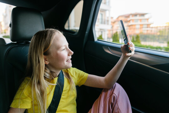 Girl clicking photo through smart phone in car