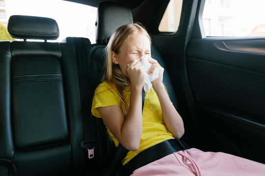 Sick girl sneezing in back seat of car
