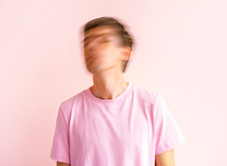 Young man wearing pink shirt shakes his head on pink background. Mental health concept. Blurred.