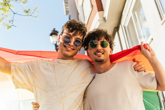 Smiling gay couple holding rainbow flag at gay pride parade