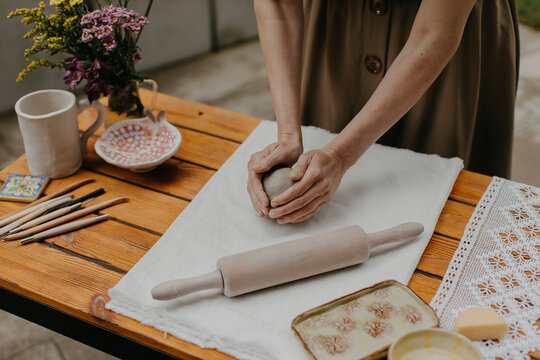 Woman kneading clay on white cloth at back yard