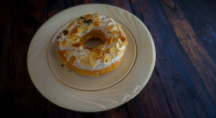 Sweet almond doughnut on a plate on wooden background