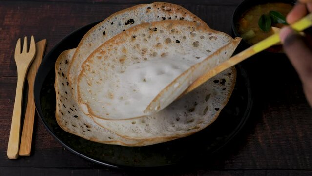 Aappam with Sambar on a wooden table. Appam or Palappam is one of the most popular and traditional breakfast in Kerala and South India.