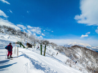 Single chair lifts in a ski resort and snowy peaks in a distant on a sunny day (Madarao Kogen, Nagano, Japan)