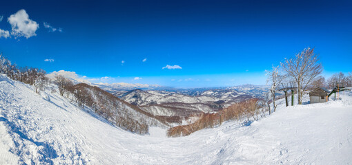 Panorama view of a steep slope and snow peaks a sunny day (Madarao Kogen, Nagano, Japan)