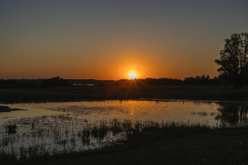 Zach&oacute;d słońća nad sadzawką we wsi Kal