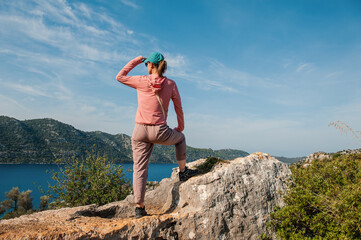 Beautiful traveler woman on mountain peak looking at the sea water