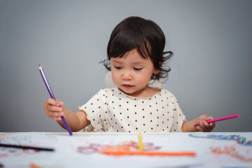 toddler baby playing and training to drawing with colored pencil on table