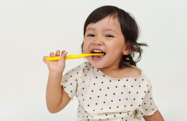 happy toddler girl brushes her teeth with smile