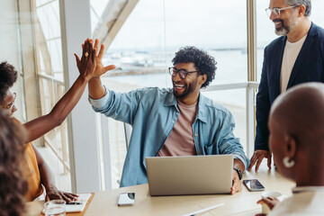 Successful business people celebrating with a high five gesture in a boardroom