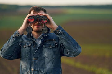 Fototapeta premium Portrait of man with binoculars that is standing outdoors on the agricultural field