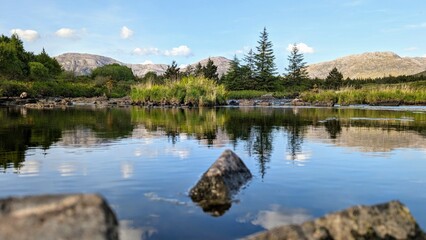 Beautiful landscape scenery, river with mountains and pine trees reflection, nature background Derryclare natural reserve at Connemara national park, county Galway, Ireland, wallpaper