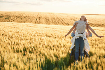 Woman in in hands of man. Lovely beautiful couple are together on the agricultural field