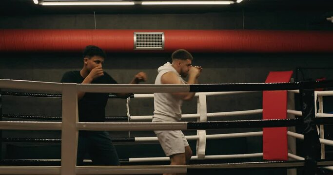 Training inside the boxing ring. A teenage practices punches with his trainer.