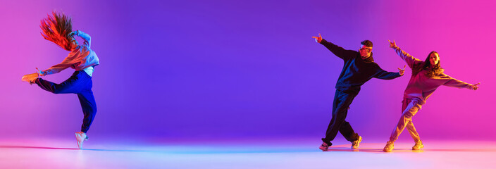 Banner. Young active couple, boys and girls dancing contemp, hip hop against gradient studio background in neon. Concept of contemporary dance style, youth, hobby, action and motion. Ad