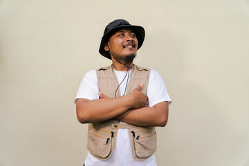  Macho asian man with beard and mustache wearing safari clothes isolated on beige background. Half body portrait of an adult Southeast Asian man posing in many styles like an adventurer © Yasuspade