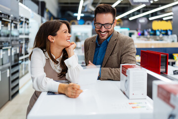 Beautiful and happy middle age couple buying consumer tech products in modern home appliances...