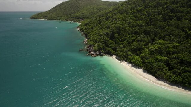 Aerial view of Nudey Beach with lush forest, mountains, and crystal clear water, Fitzroy Island, Queensland, Australia.