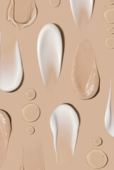 brush strokes of creamy texture of cosmetic samples on a pastel beige background