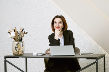 Portrait of business woman in a black business suit at desk in your office. Business portrait....