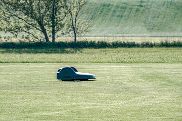 A battery-powered electric lawnmower drives across the field and cuts the grass.