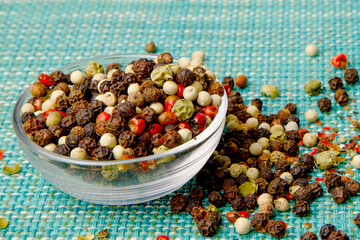 There is a bowl filled with a variety of peppercorns placed on a table