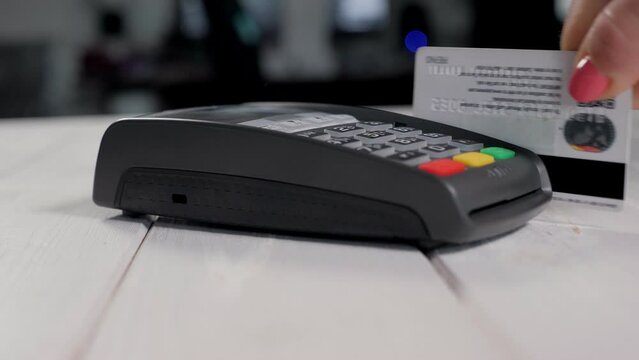 Female hands with credit card and bank terminal. Hand swiping credit card in store.