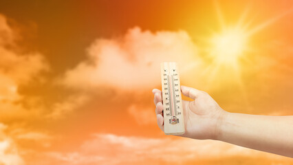 Human hand holding thermometer with hot temperature with a sky background