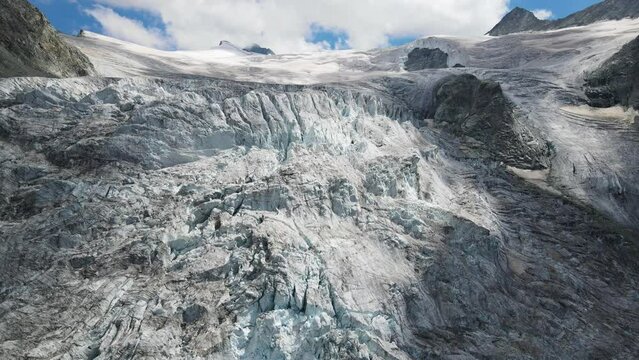 The moiry glacier in switzerland on a clear day, showcasing rugged ice formations and snowy peaks, aerial view
