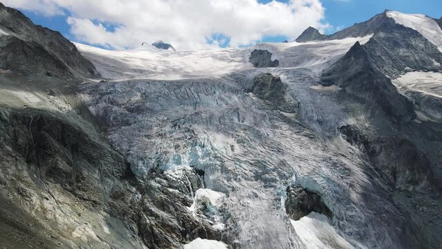 Majestic aerial view of Moiry Glacier in Switzerland with stunning ice formations and mountain peaks under blue sky