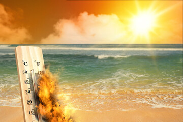 High temperature weather on summer seasons. Image of burned thermometer on a beach with sunbeam.