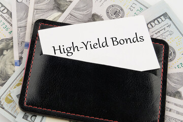 Inscription High-Yield Bonds on a business card in a leather accessory on the background of banknotes