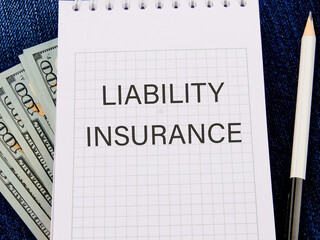 Text Liability Insurance on a notepad against the background of money