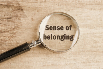 Business, sense of belonging concept. Text Sense of belonging visible through a magnifying glass on an old faded background