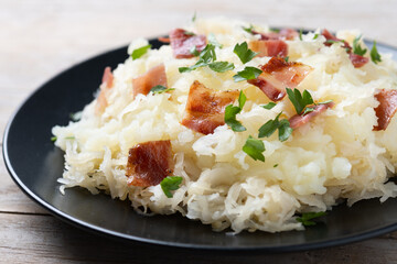 Slovak potato dumplings halusky with steamed sauerkraut and bacon on wooden table. Close up