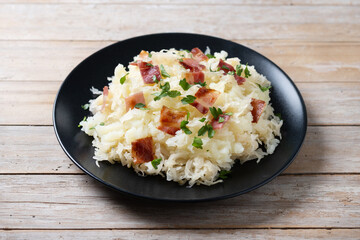 Slovak potato dumplings halusky with steamed sauerkraut and bacon on wooden table