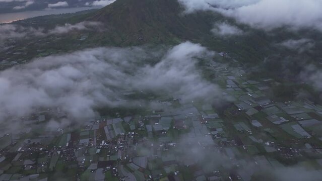 Aerial view of Batur volcano, farmland, and lake at sunrise with clouds and Pinggan, Kintamani, Bali, Indonesia.