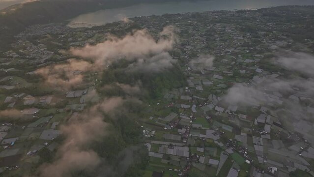 Aerial view of Batur volcano, farmland, and lake with sunrise over Pinggan, Kintamani, Bali, Indonesia.