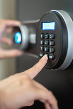 Action of people hand is unlocking to open the safe box door by pressing password on the number panel. Close-up and selective focus.