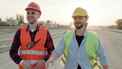Smiling builders talking, controlling work process on site