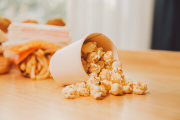 A bucket of popcorn, top-view, warm colors, light brown wooden background, flat lay, daylight macro...