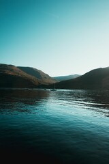 Spectacular view of a lake surrounded by majestic mountains as the sun shines on the tranquil scene