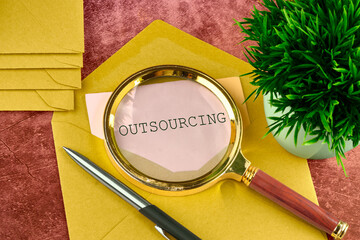 Business and outsourcing or insourcing concept. Copy space. OUTSOURCING word on a piece of paper sticking out of a mail envelope