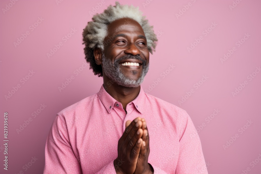 Wall mural Portrait of a glad afro-american man in his 50s joining palms in a gesture of gratitude over solid pastel color wall - Wall murals